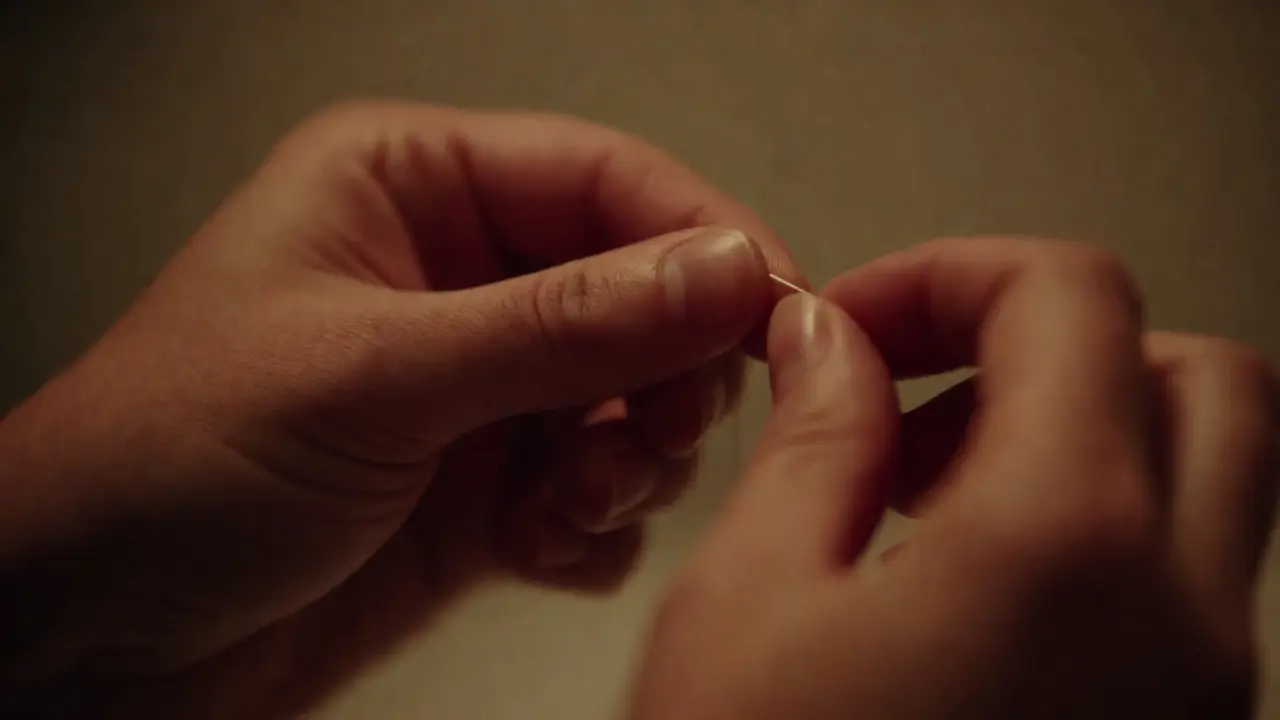 Detailní záběr na používání dentální nitě pro kontrolu povrchu zubů mezi zuby.